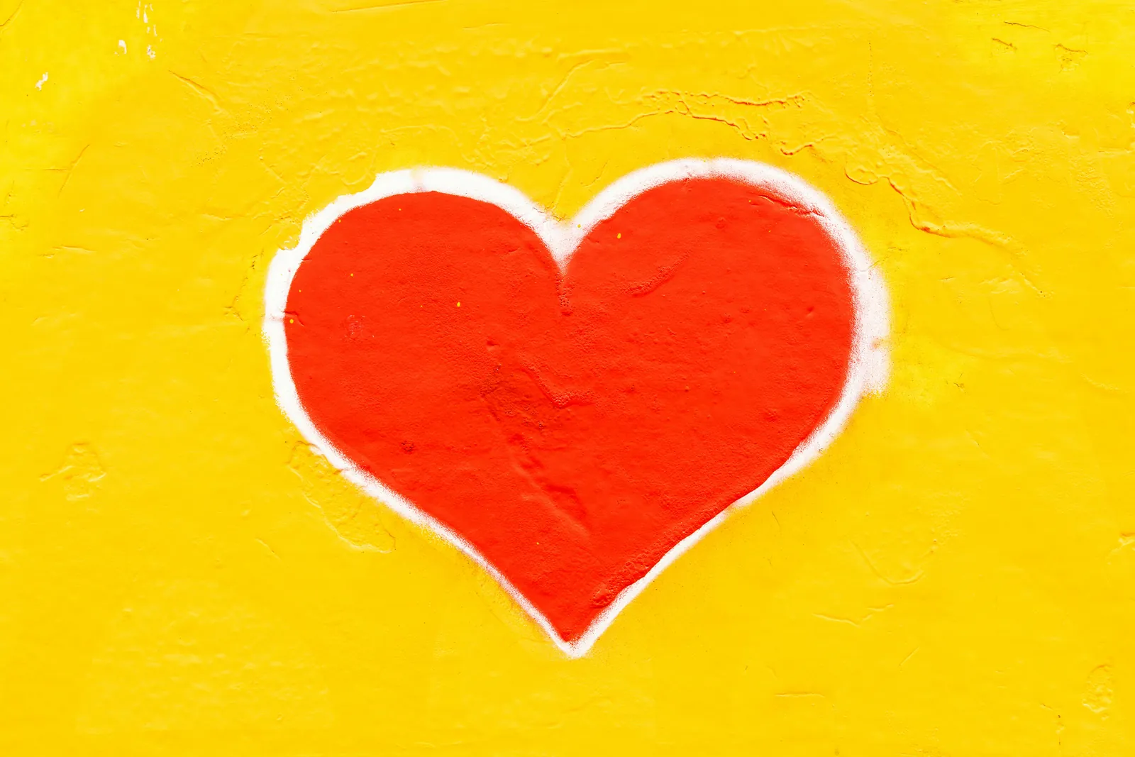 A red heart painted on a yellow wall