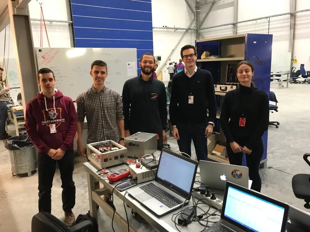 The team standing behind the experiment hardware and laptops in a hangar at Esrange
