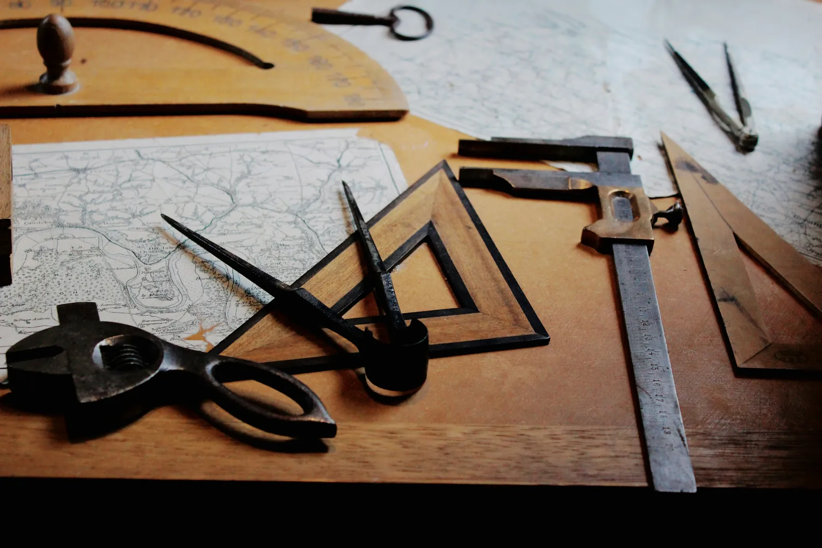 Old drafting tools, compasses and scissors on a table beside a map