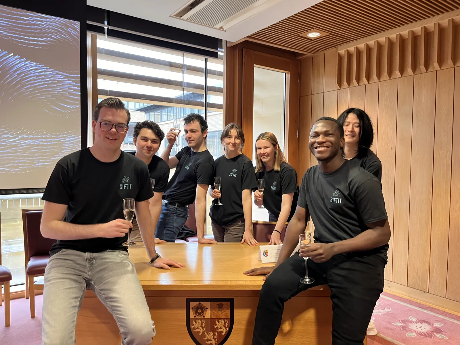 The project team smiling around a table in an Oxford college room